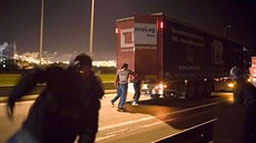 Běženci se snaží naskočit do kamionu u francouzského Calais.
