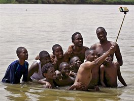 Mladí lidé v Súdánu  Hlouek mladík pózuje ke spolenému snímku v mlké vod...
