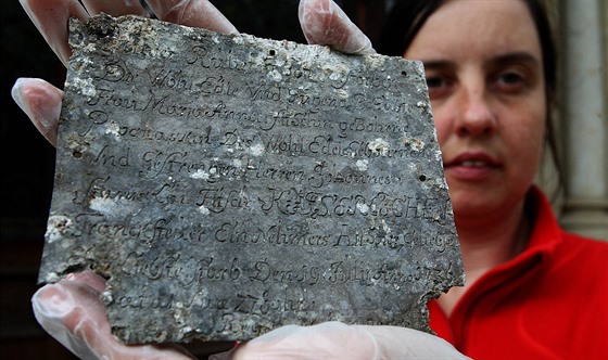 Liberecká archeoložka Michaela Bradáčová drží tabulku se jménem zemřelé ženy a...