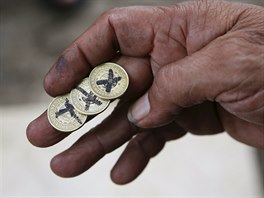 Gambler ukazuje mince, které se používají v ilegální hře zvané "Kara Y Kruz".