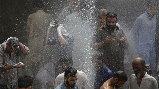 Lidé se chladí a myjí u prasklého vodovodu v Karáčí. (25. 6. 2015)