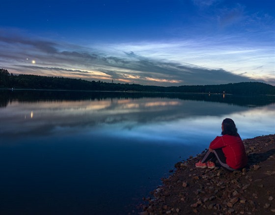 Fotografie ukazuje dívku sedící na pláži u Sečské přehrady, na obloze konjunkce...