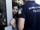 Policista se snaí uklidnit situaci u dveí aténské banky, ped ní se tlaí...