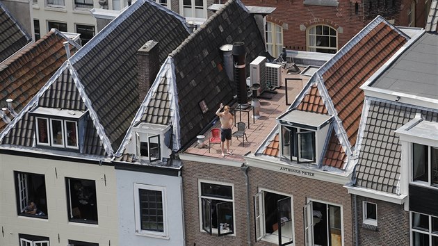 Divci sleduj projdjc peloton z oken a stech dom v centru Utrechtu.