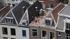 Diváci sledují projídjící peloton z oken a stech dom v centru Utrechtu.