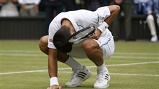 Novak Djokovi se dotýká trávy na centrálním kurtu ve Wimbledonu