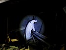 Soudní vyetovatel svítí baterkou do tunelu, který byl prokopán do federální...