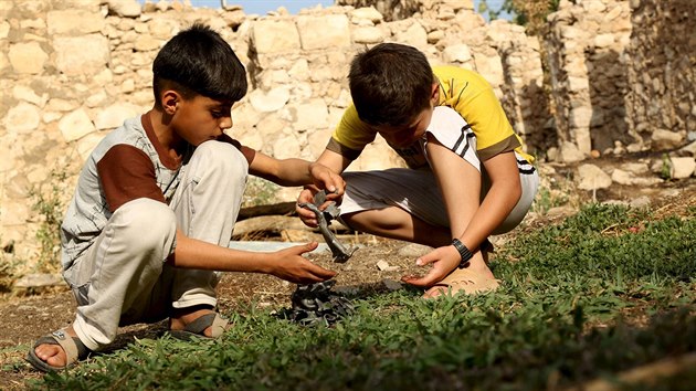 Chlapci si hraj s kousky kovu, kter nali u krteru, kter vznikl po nletu tureck armdy (29. ervence 2015).