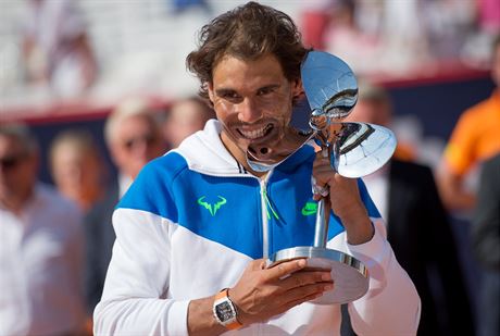 panlský tenista Rafael Nadal ochutnává trofej z antukového turnaje v Hamburku.