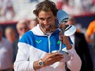 panlský tenista Rafael Nadal ochutnává trofej z antukového turnaje v Hamburku.