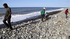 Lidé na Réunionu procházejí plá� a sna�í se najít dal�í �ást letadla (1. srpna...