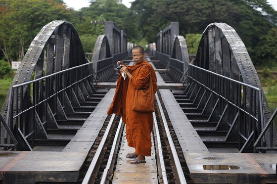 Buddhistický mnich si fotografuje most pes eku Kwai v thajské provincii...