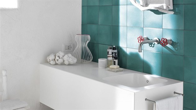 Akvamarínové rustikální dlaždice kontrastují s umyvadlem zasazeným do koupelnové desky z corianu.
