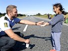 Dánský policista si hraje s jednou z malých uprchlic na silnici smrem do...
