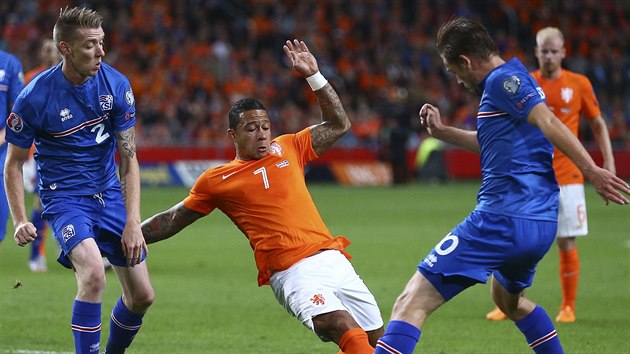 Nizozemsk fotbalista Memphis Depay (v oranovm) se neprosadil pes islandsk dvojblok Gylfie Sigurdsson (vpravo) a Birkir Saeversson.