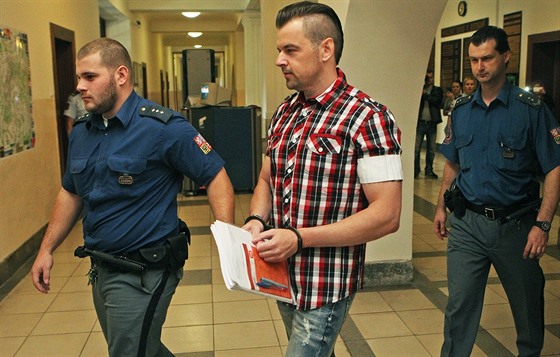 Justiční stráž přivádí Petra Kramného do jednací síně.