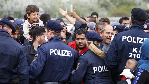 Rakout policist se sna zklidnit dav migrant u msta Nickelsdorf nedaleko maarskch hranic. (14. z 2015)