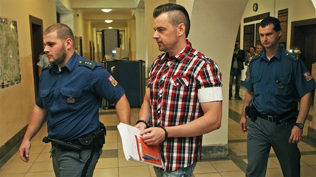Justiční stráž přivádí Petra Kramného do jednací síně.
