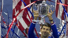 OSLAVA VÍTĚZE. Novak Djokovič s pohárem pro vítěze tenisového US Open v záplavě...