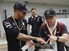 Lewis Hamilton (vlevo) dává autogram japonskému fanoukovi.