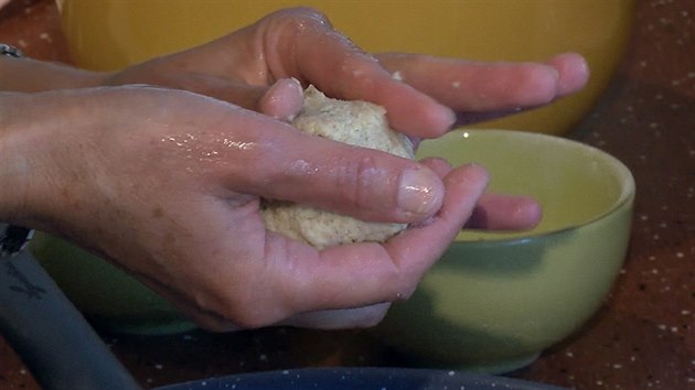 Placičku těsta na navlhčené dlani naplňte ovocem (případně slanou náplní, viz text), pečlivě uzavřete a hotový knedlík zakulaťte.  
