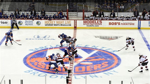 Pavel Zacha zastupuje New Jersey (v bílých dresech) na úvodním buly zápasu s New York Islanders, proti němu stojí  John Tavares.