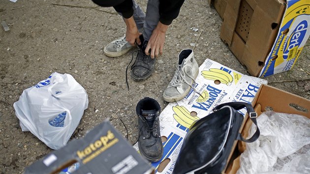 Ped cestou ze Srbska do Chorvatska si uprchlci zkouej nov boty, kter jim poskytly humanitrn organizace (1. jna 2015).