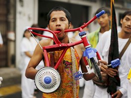 A devotee of the Chinese Bang Neow shrine walks with a tricycle pierced...