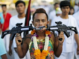 A devotee of the Chinese Ban Tha Rue shrine walks with guns pierced through...