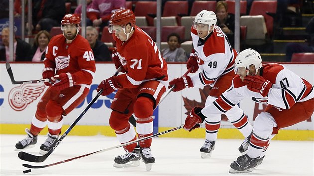 Michal Jordn z Caroliny (vpravo) se pokou doshnout na puk, kter vede Dylan Larkin z Detroitu.