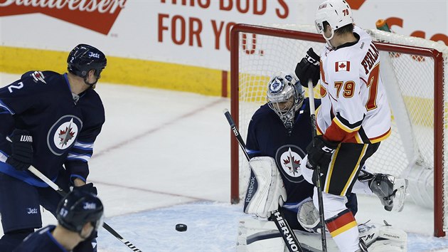 Brank Winnipegu Ondej Pavelec hled puk, ped nm clon Michael Ferland z Calgary.