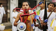 A devotee of the Chinese Bang Neow shrine walks with a tricycle pierced...