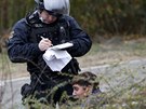 Policista zasahuje u rozmíky mezi migranty ekajícími na registraci ve...