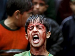 A Shi'ite Muslim boy shouts religious slogans after flagellating himself during...