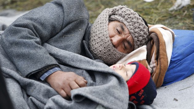 Muž s dítětem odpočívají na zemi při čekání na slovinsko-rakouské hranici (30. října 2015)