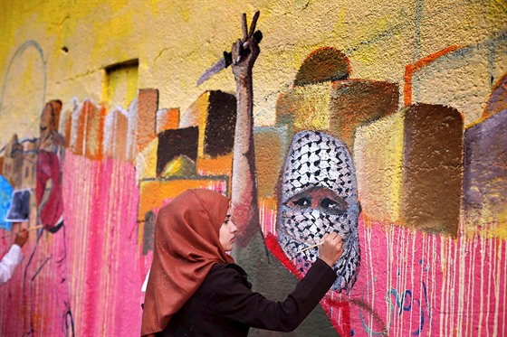 Palestinka v Gaze maluje propagandistický murál.