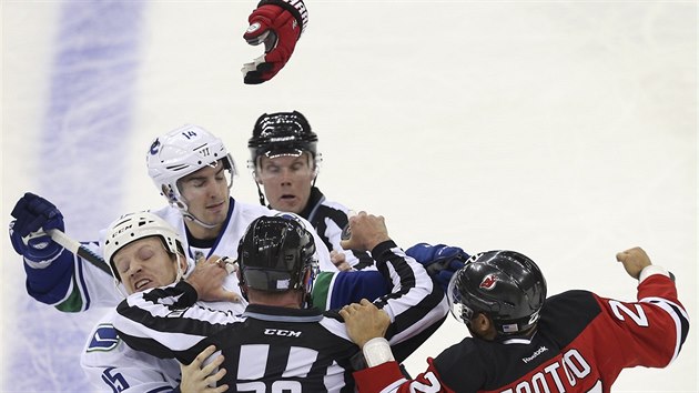 Jordin Tootoo (vpravo) z New Jersey v potyce s  Alexandrem Burrowsem (druh zleva) a Derekem Dorsettem z Vancouveru.