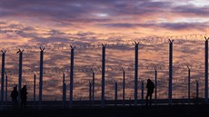 Uprchlíci postávají u plotu, který vyrostl u dálnice ve francouzském Calais (3....
