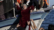 Migranti pomáhají �en� z lodi po p�iplutí na �ecký Lesbos (7. listopad 2015)