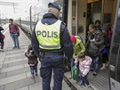 védská policie shromauje migranty, kteí picestovali vlakem pes most z...