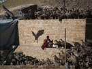 A Buddhist monk collects his belongings as vultures gather around a body of a...