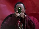 A Tibetan Buddhist monk take pictures with his smartphone of a daily chanting...