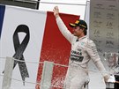 Nico Rosberg slaví triumf v Brazílii, za ním francouzská vlajka s ernou páskou...