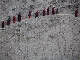 Monks and nuns walk across a steep hill back to their dormitory after attending...