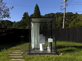 WC kabinka s prosklenými stěnami stojí na oploceném pozemku na nádraží Itabu...