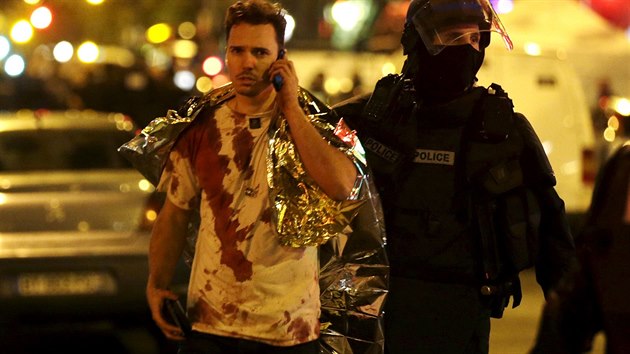 Policista u koncertní síně Bataclan v Paříži doprovází jednoho ze zraněných po teroristickém útoku. (13. listopadu 2015)