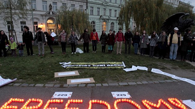 Lidé se drží za ruce před svítícím nápisem, který v překladu znamená „svoboda“. Chtějí tak podpořit uprchlíky držené v českých detenčních centrech.