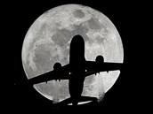 ÚPLNĚK. Dopravní letadlo na pozadí Měsíce nad městem Whittier v Kalifornii.