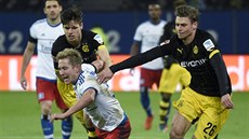 Lewis Holtby (uprost�ed) z Hamburku padá po souboji s Lukaszem Piszczekem...