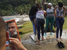 A Cuban migrant shaves his beard as others freshen up after they crossed the...